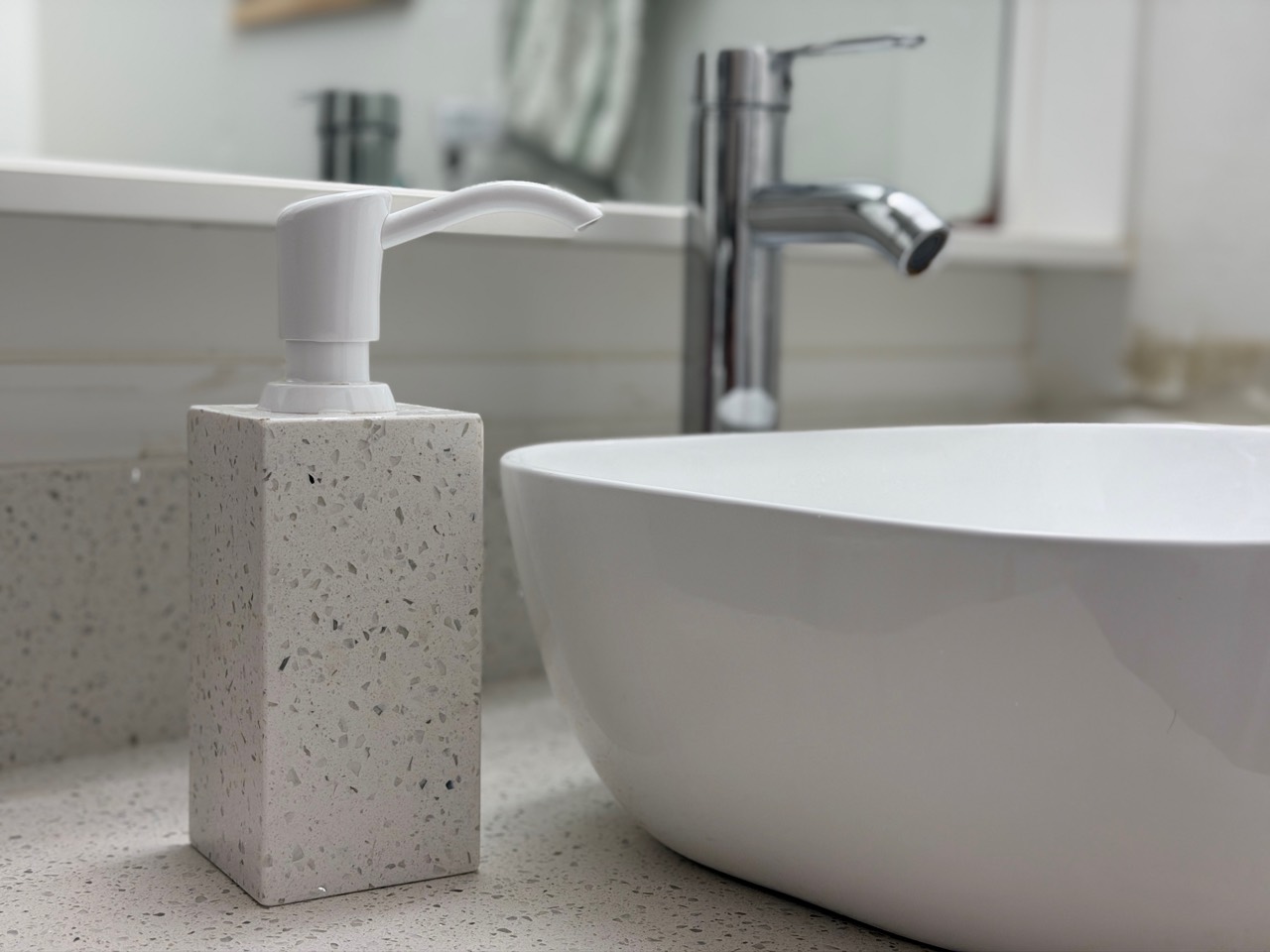 Speckled stone soap dispenser beside a white vessel sink