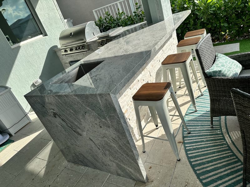 Grey granite outdoor bar with a waterfall end, undermount sink and stools