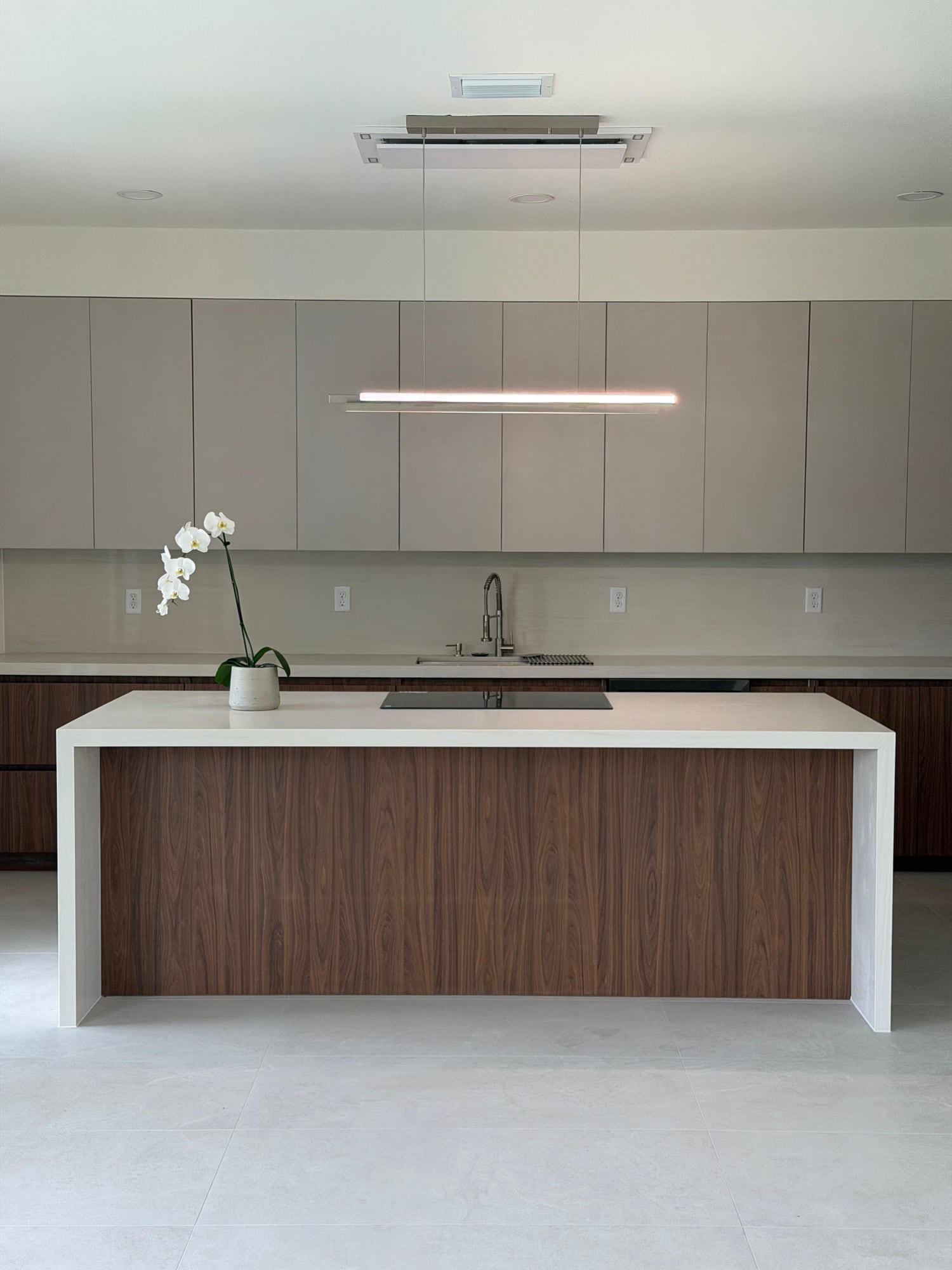 White waterfall island with a wood cabinet front in a contemporary kitchen