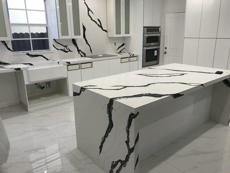 White quartz waterfall island with bold black veining and a matching full-height kitchen backsplash